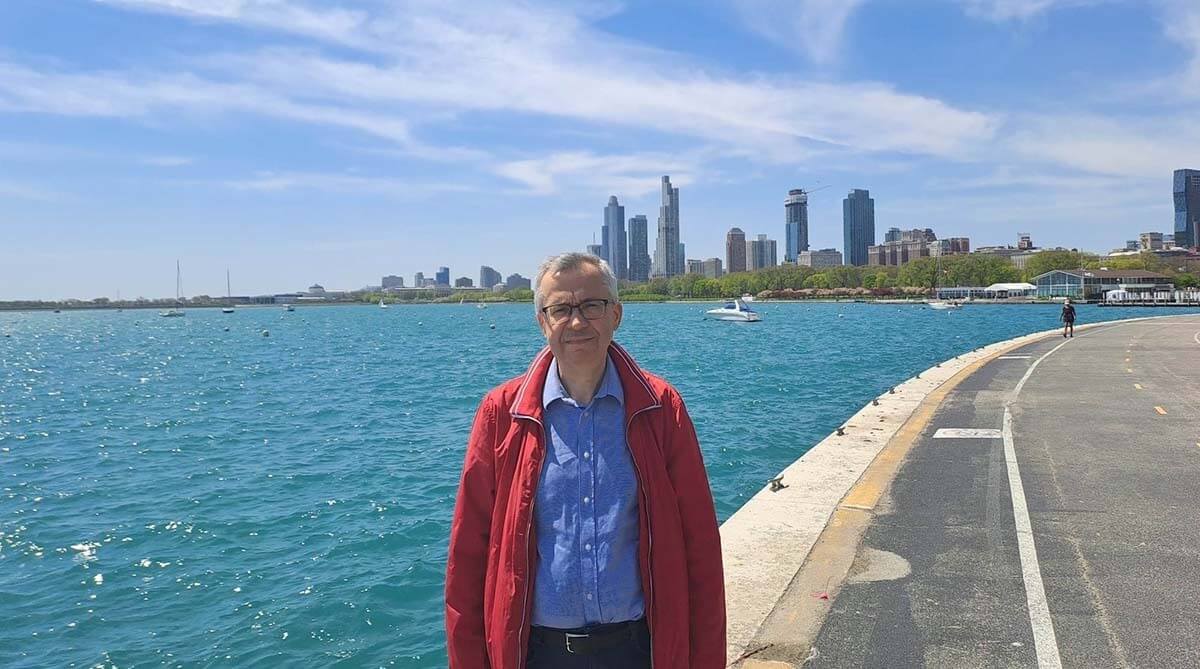 Andrzej Podraza standing in front of Lake Michigan with a view of Chicago.